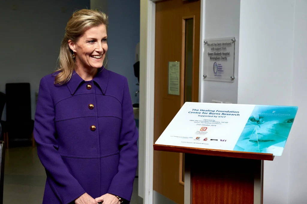 HRH The Duchess of Edinburgh in purple jacket standing beside an informational plaque at The Healing Foundation Centre for Burns Research.