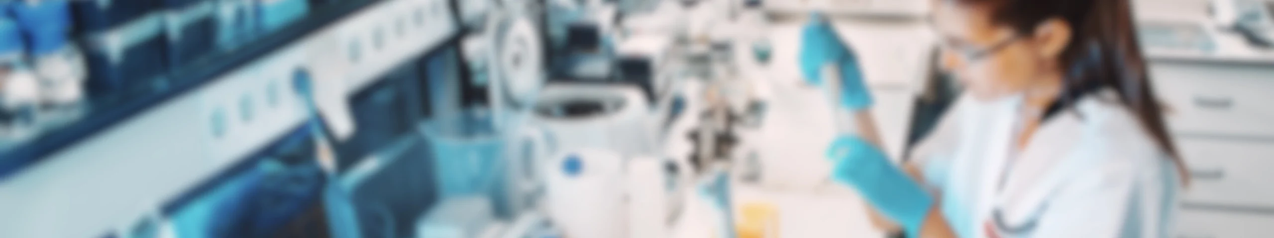 Laboratory researcher in white coat working with scientific equipment and samples in a modern medical research facility.