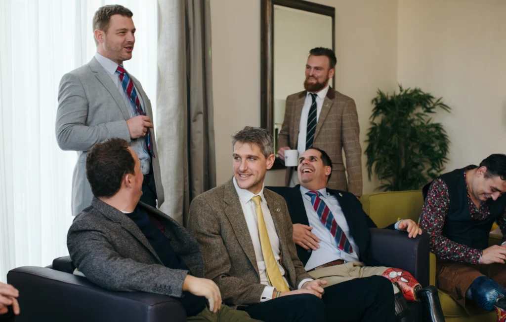Group of professional men in business attire having a casual conversation in an office setting.