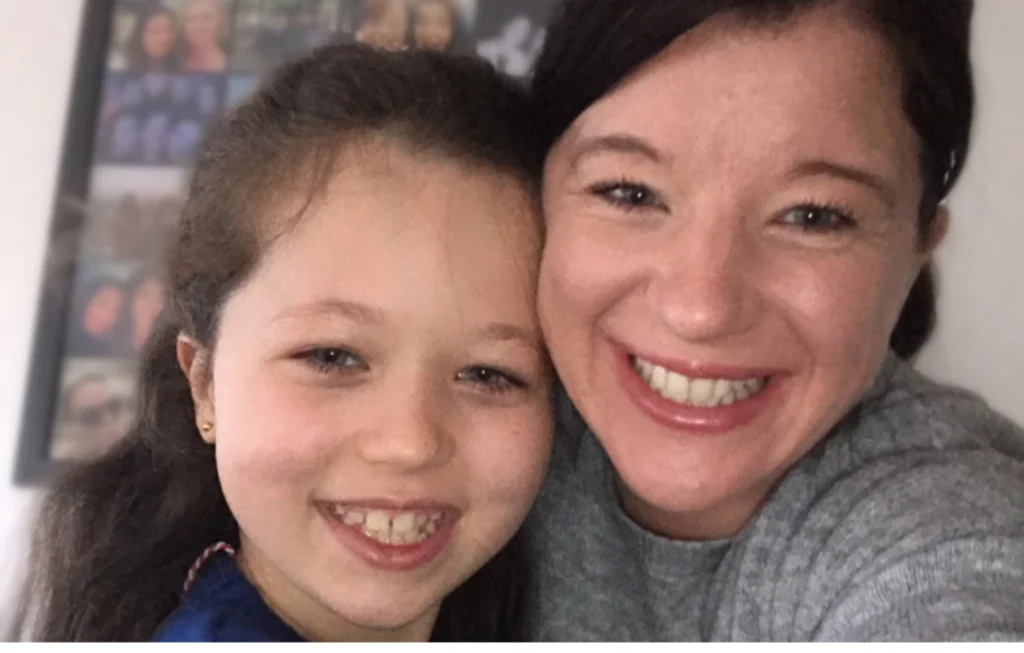Two smiling people posing together for a close-up portrait photo indoors.