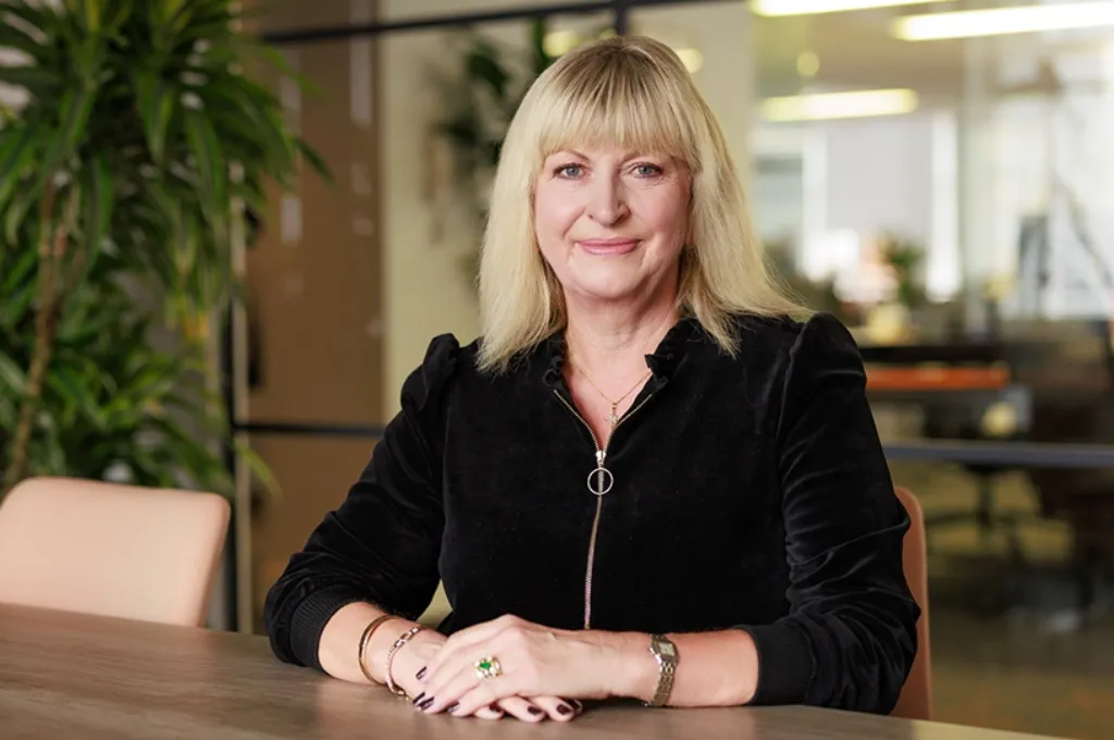 Alison Clarke, team member at Scar Free Foundation, seated at desk in professional office setting wearing black velvet jacket.