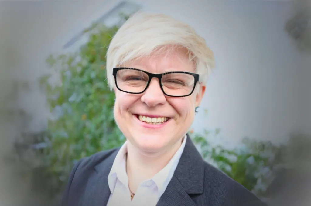 Catherine Attwood, team member at Scar Free Foundation, wearing glasses and dark blazer, smiling at camera.