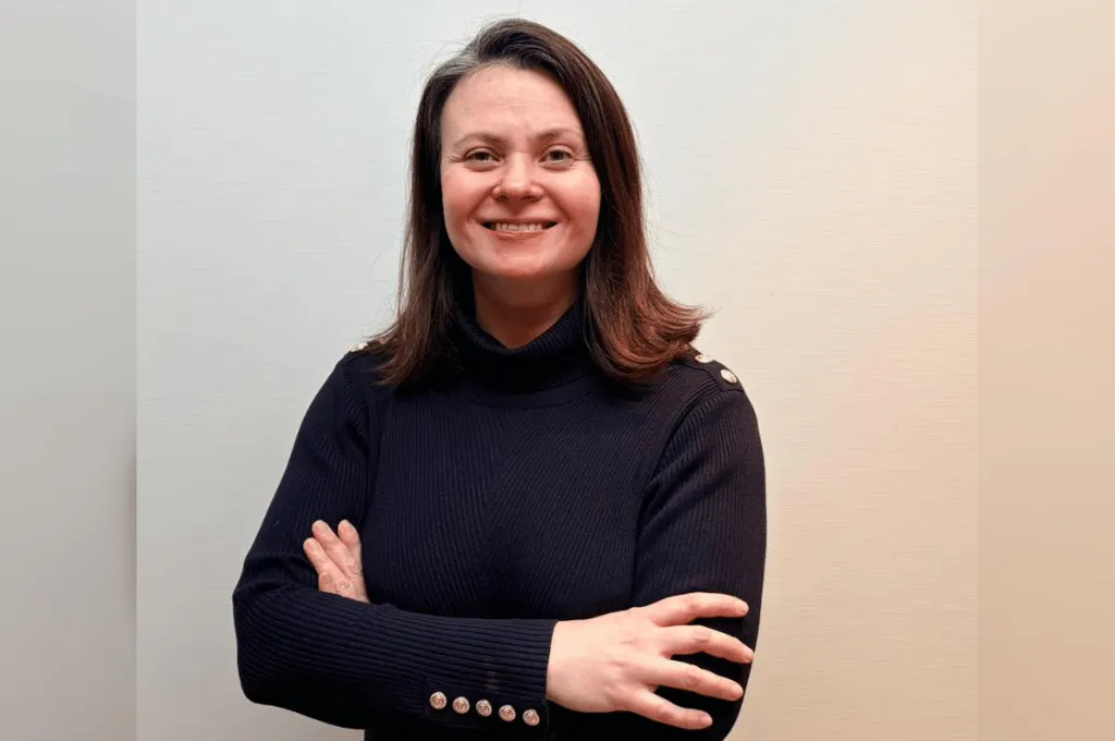 Galia Wells, Scar Free Foundation team member, smiling with arms crossed wearing a dark turtleneck.