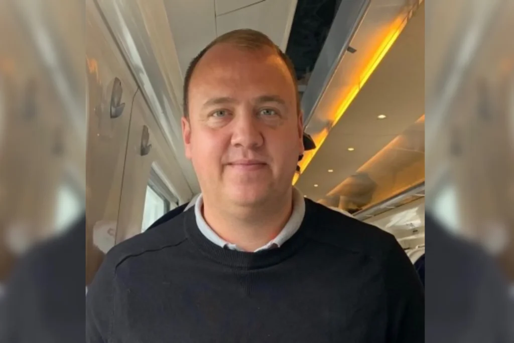 Robert Dickinson, team member, portrait taken inside an airplane cabin wearing black sweater.