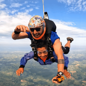 Hemani and her skydive instructor soar through the sky attached to a parachute with green fields below