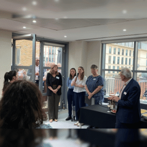 Dr Rebecca Richardson, Plastic Surgery Registrar Olivia Hartrick, Dr Mary Keeling, Charlotte Coates, and Lt Gen (Rtd) Richard Nugee stand against a floor to ceiling office window space to present a researcher Q&A. A view of London's rooftops and buildings can be seen in the background.